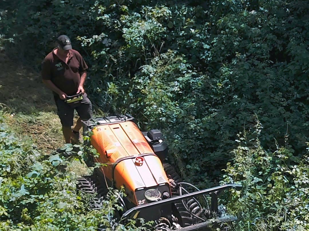 Débroussaillage radiocommandé — L'opérateur pilote depuis le terrain plat, le porte-outils ouvre la friche